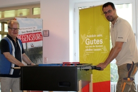 P. Jörg Widmann und Schreiner Michael Bräu am Kicker, den die Schreinerei dem Don Bosco Zentrum geschenkt hat